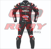Front profile of Marco Bezzecchiās Aprilia Racing 2025 MotoGP suit in a sleek black and red colorway. Sponsor logos include Sterilgarda, Sky WiFi, Piaggio Group, MotoGP, and Aprilia. Detailed with RUBY branding on the collar and arms.